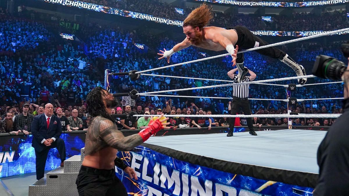 Sami Zayn in the midst of an outside dive on Roman Reigns
